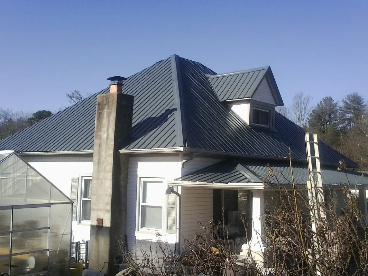 Dark blue standing seam metal roof on a white farmhouse with dormer — Slate & Tile Roof Repair by Roofing Brothers in South Hadley