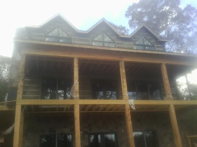 Dormers and porch framing on a large log home under construction — Roof Coating work by our crew in South Hadley