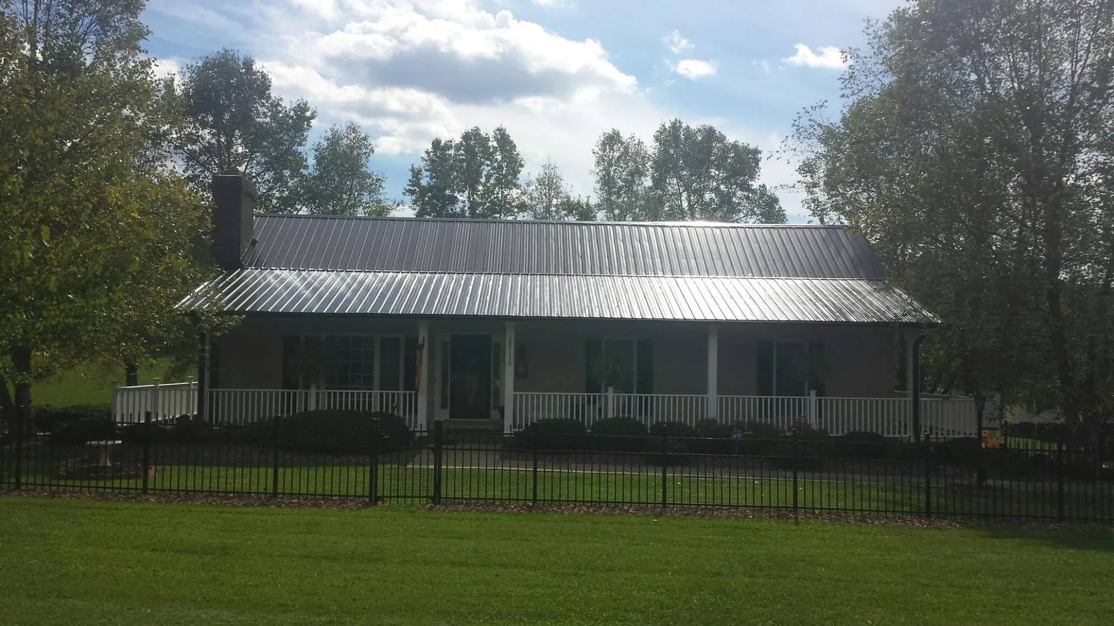 Gray metal roof on a brick ranch with a full width front porch — Gutter Guard Installation work by our crew in South Hadley