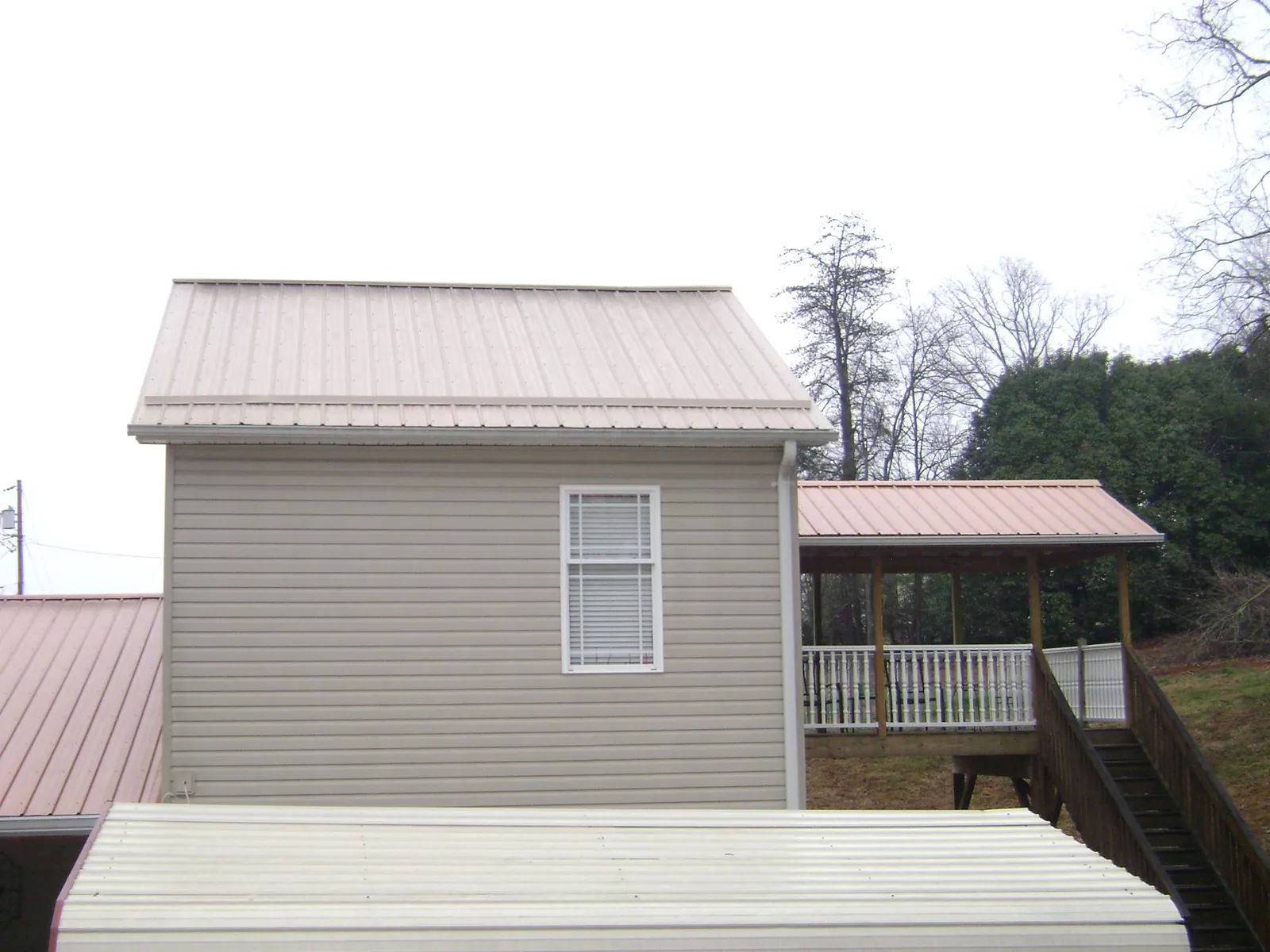 Tan metal roofs on a two story addition and attached porch, from a Roof Replacement job in South Hadley