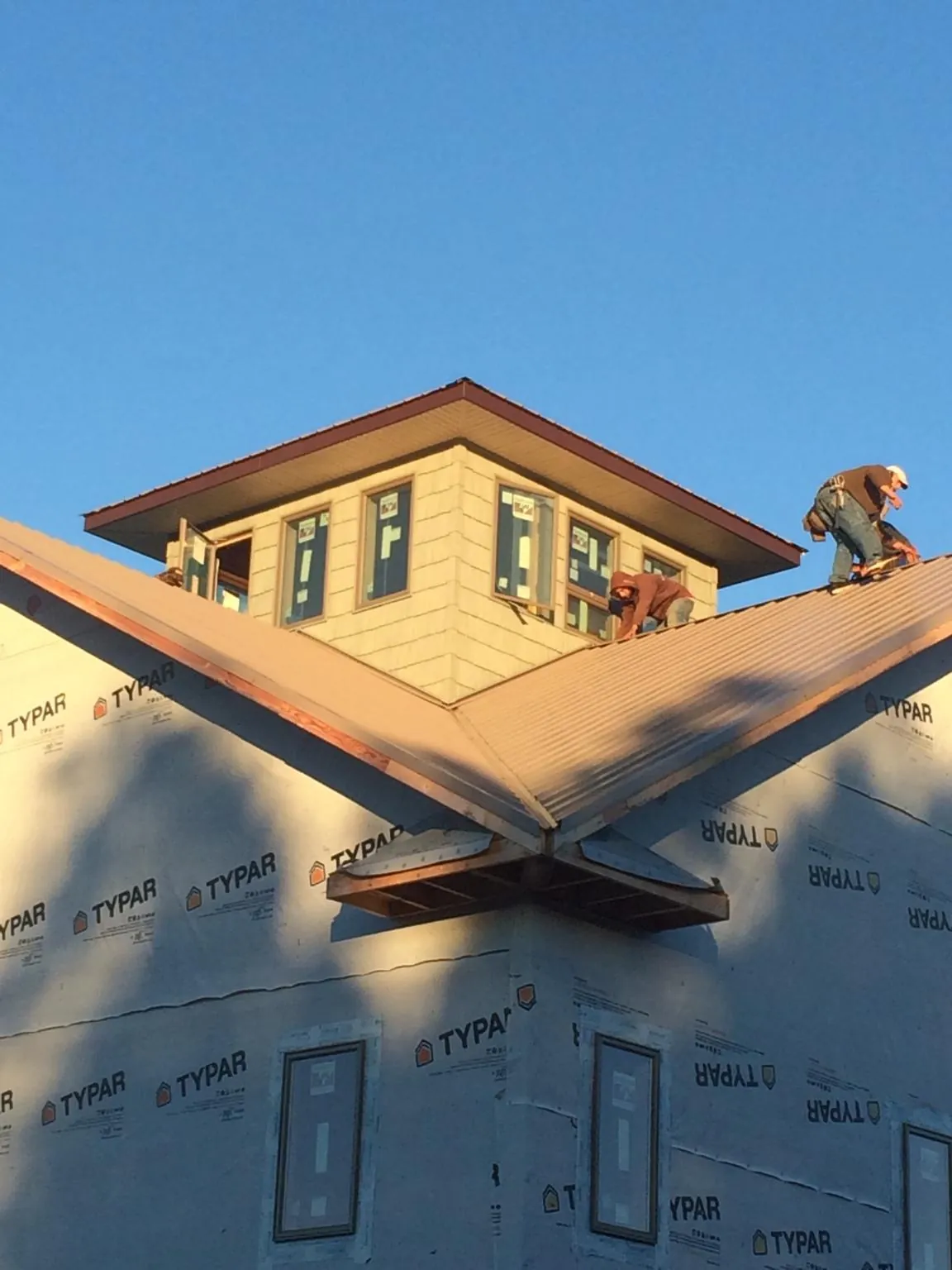 Roofers working around a rooftop cupola on a new metal roof at sunset — Roof Waterproofing in South Hadley by Roofing Brothers
